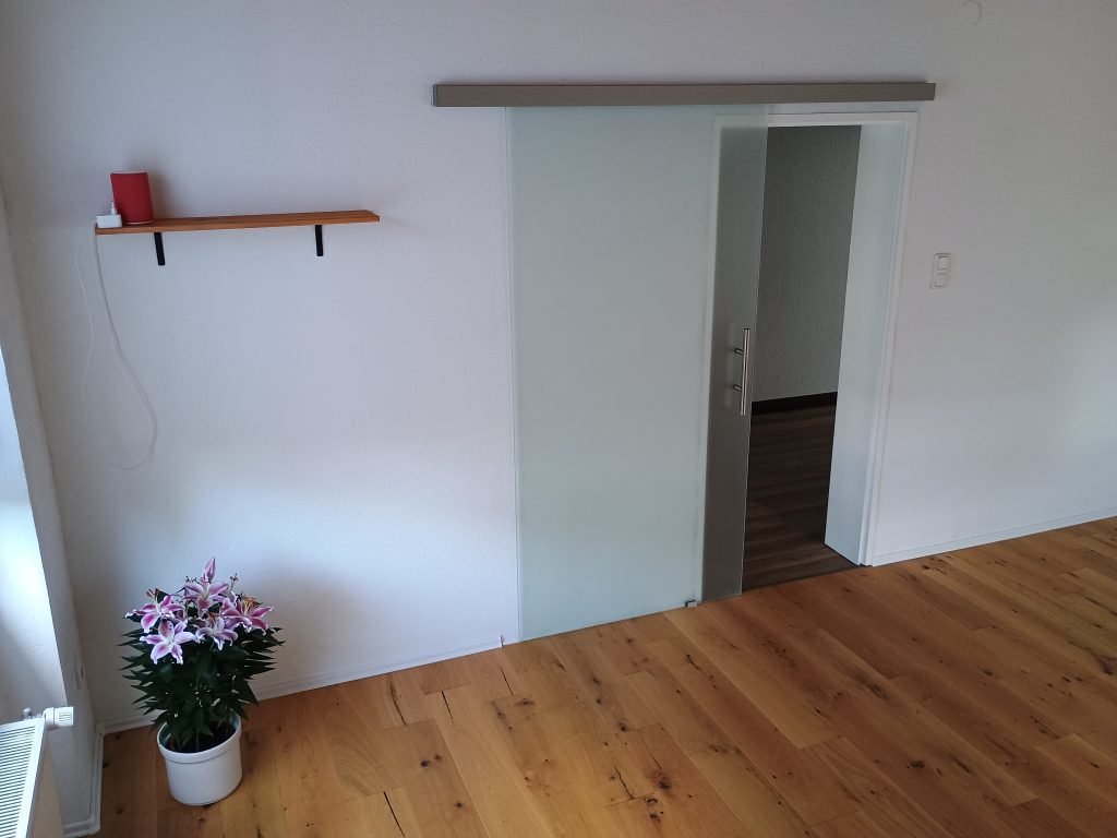 Heller Kursraum mit Holzboden und Glastür